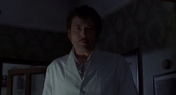 Movie still from “Frenzy” (1972), directed by Alfred Hitchcock – A man wearing a lab coat standing in the dark; Close Up shot, Low angle