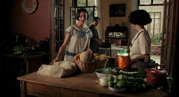 Movie still from “Frida” (2002), directed by Julie Taymor – A woman standing in front of a table filled with vegetables; Medium shot, Over the shoulder angle