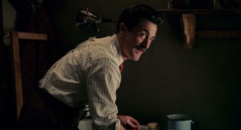Movie still from “Frida” (2002), directed by Julie Taymor – A man in a striped dress shirt and red neck tie smiling; Medium shot, Low angle