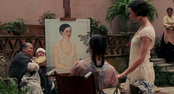 Movie still from “Frida” (2002), directed by Julie Taymor – A woman sitting in front of an easel painting a picture of herself; Medium shot, Over the shoulder angle