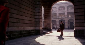 Movie still from “Frida” (2002), directed by Julie Taymor – A man walking down a street under an archway; Wide shot, Low angle