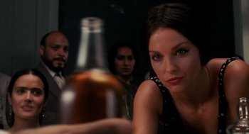 Movie still from “Frida” (2002), directed by Julie Taymor – A woman sitting in front of a large bottle of alcohol; Close Up shot, Over the shoulder angle