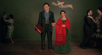 Movie still from “Frida” (2002), directed by Julie Taymor – A man and a woman standing next to each other holding hands; Medium shot, Low angle