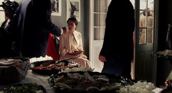 Movie still from “Frida” (2002), directed by Julie Taymor – A group of people standing around a table with food on top of it; Medium shot, High angle