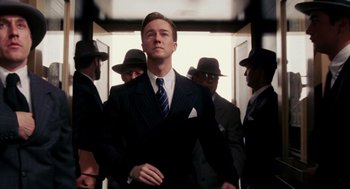 Movie still from “Frida” (2002), directed by Julie Taymor – A man in a suit and tie standing in front of a group of men; Medium shot, Low angle