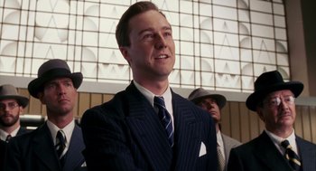 Movie still from “Frida” (2002), directed by Julie Taymor – A man wearing a suit and tie standing in front of other men; Medium shot, Low angle