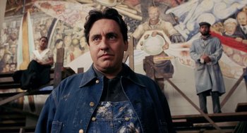 Movie still from “Frida” (2002), directed by Julie Taymor – A man standing in front of a painting; Close Up shot, Low angle