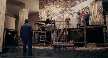 Movie still from “Frida” (2002), directed by Julie Taymor – A group of people standing in front of a mural; Wide shot, Low angle