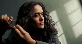 Movie still from “Frida” (2002), directed by Julie Taymor – A woman with long black curly hair sitting in a room; Close Up shot, Low angle