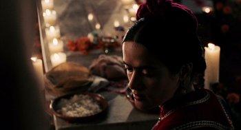 Movie still from “Frida” (2002), directed by Julie Taymor – A woman sitting in front of a plate of food; Close Up shot, Over the shoulder angle