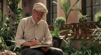 Movie still from “Frida” (2002), directed by Julie Taymor – An older man writing in a notebook while sitting on a bench; Medium shot, Low angle