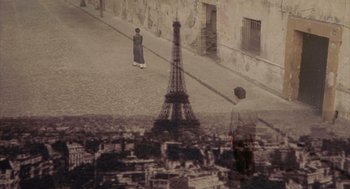 Movie still from “Frida” (2002), directed by Julie Taymor – A man standing on the sidewalk in front of the eiffel tower; Wide shot, High angle