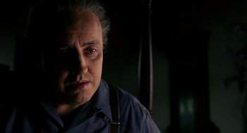 Movie still from “Frida” (2002), directed by Julie Taymor – An older man wearing a blue shirt and suspenders; Close Up shot, Over the shoulder angle