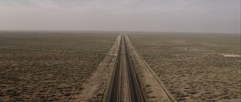 Movie still from “Friday Night Lights” (2004), directed by Peter Berg – An aerial view of an empty road in the middle of the desert; Extreme Wide shot, High angle