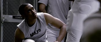 Movie still from “Friday Night Lights” (2004), directed by Peter Berg – A basketball player in a huddle; Medium shot, Over the shoulder angle