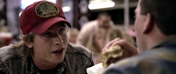 Movie still from “Friday Night Lights” (2004), directed by Peter Berg – A person sitting at a table eating a sandwich; Close Up shot, Over the shoulder angle