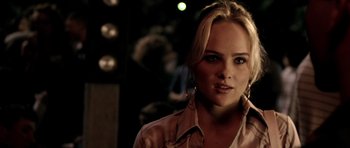 Movie still from “Friday Night Lights” (2004), directed by Peter Berg – A woman with blonde hair wearing a pink shirt; Close Up shot, Over the shoulder angle