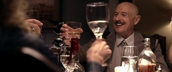Movie still from “Friday Night Lights” (2004), directed by Peter Berg – A man sitting at a table with a glass of wine; Close Up shot, Over the shoulder angle