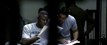 Movie still from “Friday Night Lights” (2004), directed by Peter Berg – Two young men working on papers in a dark room; Medium shot, High angle
