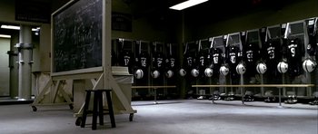 Movie still from “Friday Night Lights” (2004), directed by Peter Berg – A room filled with a bunch of black and white baseball uniforms; Wide shot, High angle
