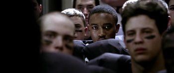Movie still from “Friday Night Lights” (2004), directed by Peter Berg – A group of men standing next to each other in a room; Close Up shot, Over the shoulder angle