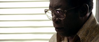 Movie still from “Friday Night Lights” (2004), directed by Peter Berg – An older man wearing glasses looking off into the distance; Close Up shot, Low angle