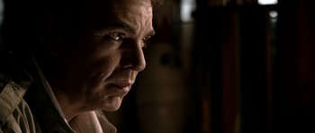 Movie still from “Friday Night Lights” (2004), directed by Peter Berg – A man's face in a dimly - lit room; Close Up shot, Low angle