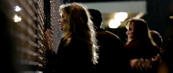 Movie still from “Friday Night Lights” (2004), directed by Peter Berg – A woman standing next to a man in a dark room; Close Up shot, Over the shoulder angle