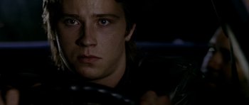 Movie still from “Friday Night Lights” (2004), directed by Peter Berg – A young man sitting in a car with a steering wheel; Close Up shot, Over the shoulder angle
