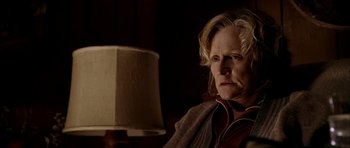 Movie still from “Friday Night Lights” (2004), directed by Peter Berg – A woman sitting in front of a lamp in a dark room; Close Up shot, Over the shoulder angle