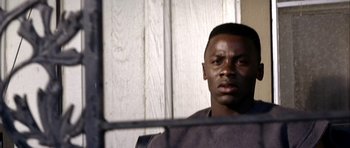 Movie still from “Friday Night Lights” (2004), directed by Peter Berg – A man with a black shirt is behind bars; Close Up shot, High angle