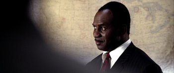 Movie still from “Friday Night Lights” (2004), directed by Peter Berg – A man in a suit and tie looking to his left; Close Up shot, Over the shoulder angle