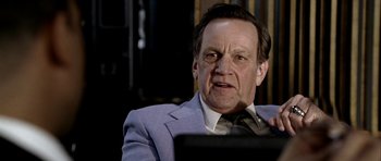 Movie still from “Friday Night Lights” (2004), directed by Peter Berg – An older man wearing a suit and tie looking at a computer screen; Close Up shot, Low angle