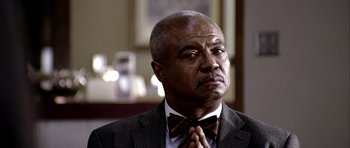 Movie still from “Friday Night Lights” (2004), directed by Peter Berg – An older man wearing a suit and bow tie; Close Up shot, Low angle