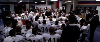 Movie still from “Friday Night Lights” (2004), directed by Peter Berg – A group of football players sitting in front of a coach; Wide shot, High angle