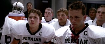 Movie still from “Friday Night Lights” (2004), directed by Peter Berg – A group of young men standing next to each other in football uniforms; Close Up shot, Over the shoulder angle