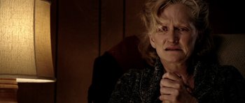 Movie still from “Friday Night Lights” (2004), directed by Peter Berg – An older woman sitting in a chair with her hand on her chin; Close Up shot, Over the shoulder angle