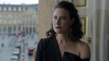 Movie still from “Emily in Paris” (2020), created by Darren Star – A woman in a black dress is standing in front of a building; Close Up shot, Over the shoulder angle