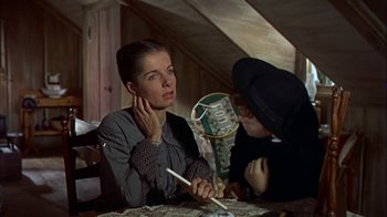 Movie still from “Friendly Persuasion” (1956), directed by William Wyler – A woman sitting at a table with another woman holding a pen; Close Up shot, Over the shoulder angle