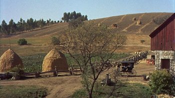 Movie still from “Friendly Persuasion” (1956), directed by William Wyler – An old fashioned buggy is parked in a field near a hay stack; Extreme Wide shot, High angle