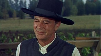 Movie still from “Friendly Persuasion” (1956), directed by William Wyler – An older man wearing a black hat and a vest; Close Up shot, Over the shoulder angle