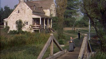 Movie still from “Friendly Persuasion” (1956), directed by William Wyler – Two people walking down a wooden path in front of a house; Extreme Wide shot, High angle