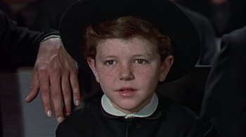 Movie still from “Friendly Persuasion” (1956), directed by William Wyler – A young boy wearing a black hat and a white shirt; Close Up shot, High angle