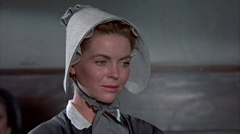Movie still from “Friendly Persuasion” (1956), directed by William Wyler – A woman wearing a white hat and a gray dress; Close Up shot, Low angle