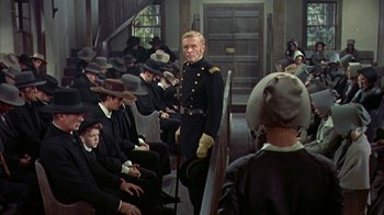 Movie still from “Friendly Persuasion” (1956), directed by William Wyler – A group of men sitting in front of each other in a room; Medium shot, High angle