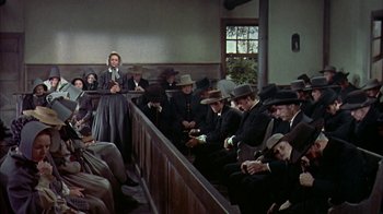 Movie still from “Friendly Persuasion” (1956), directed by William Wyler – A woman is speaking in front of a group of men; Wide shot, Low angle