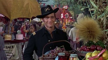 Movie still from “Friendly Persuasion” (1956), directed by William Wyler – A man wearing a black hat standing next to a basket of grapes; Medium shot, Over the shoulder angle