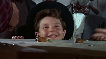 Movie still from “Friendly Persuasion” (1956), directed by William Wyler – A young boy wearing a cowboy hat and smiling at the camera; Close Up shot, Low angle