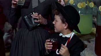 Movie still from “Friendly Persuasion” (1956), directed by William Wyler – A young boy wearing a hat and holding a glass of wine; Medium shot, High angle