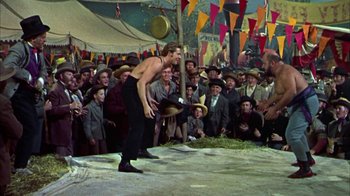 Movie still from “Friendly Persuasion” (1956), directed by William Wyler – A crowd of people are watching a man in a hat; Wide shot, Low angle